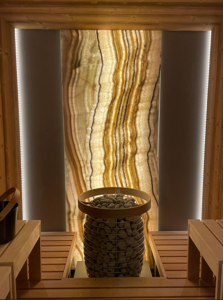 Sauna heater with stones in front of a backlit onyx feature wall